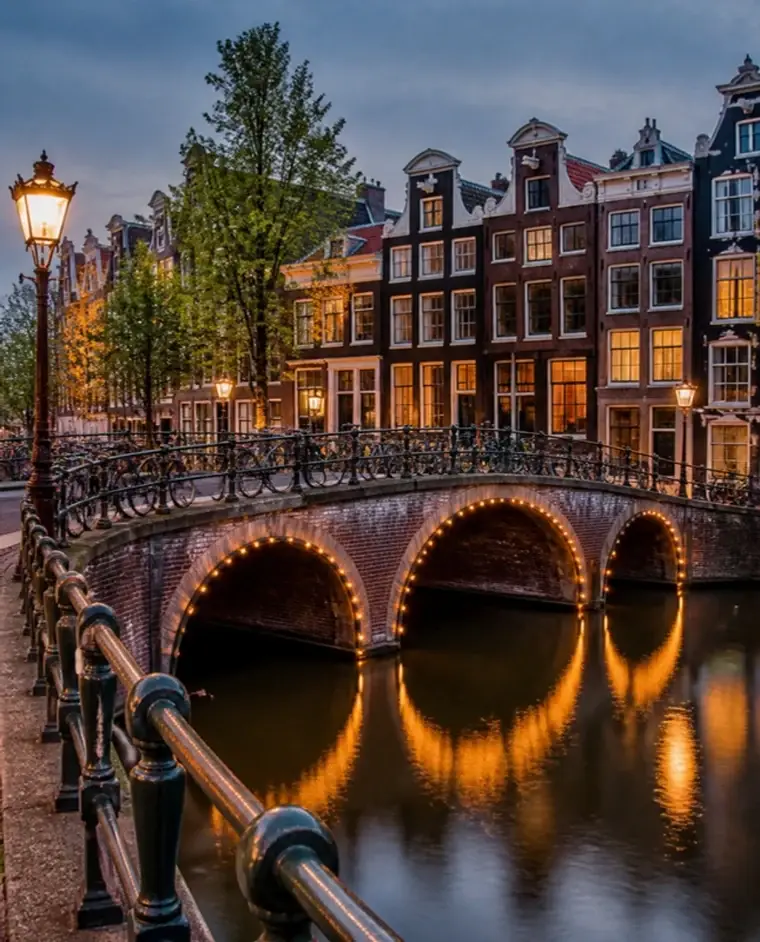 Ponte iluminada sobre um canal de Amsterdã, ao anoitecer